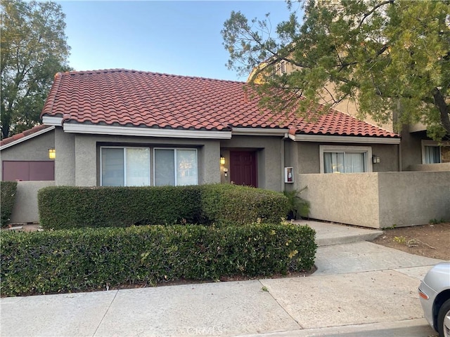 view of front facade featuring a fenced front yard, a tile roof, and stucco siding