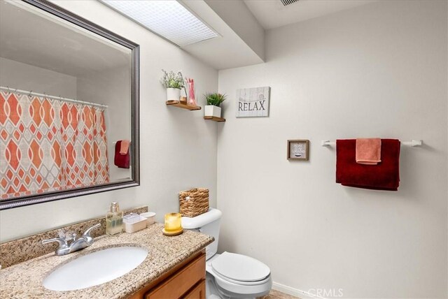 full bath featuring baseboards, a shower with shower curtain, vanity, and toilet