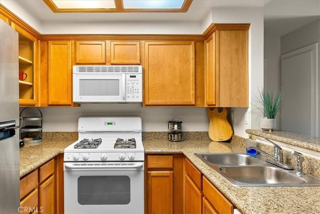 kitchen featuring light countertops, white appliances, a sink, and brown cabinets