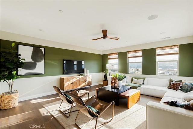 living area featuring baseboards, visible vents, ceiling fan, and wood finished floors