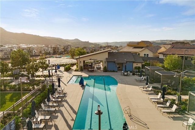 pool featuring a residential view, a mountain view, fence, and a patio area