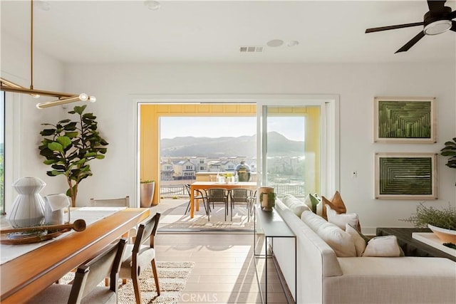 living room with ceiling fan, visible vents, and wood finished floors