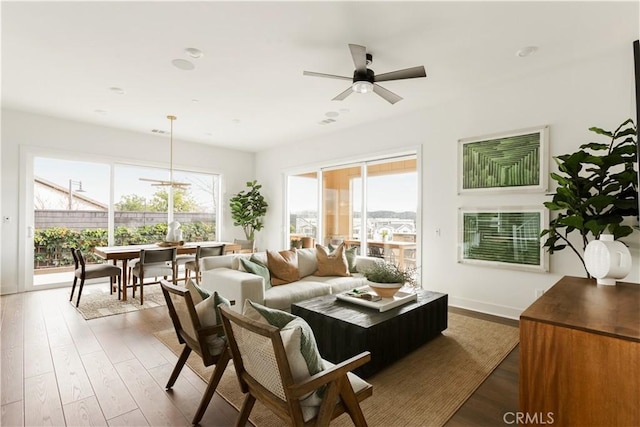 living area featuring a ceiling fan, baseboards, and wood finished floors