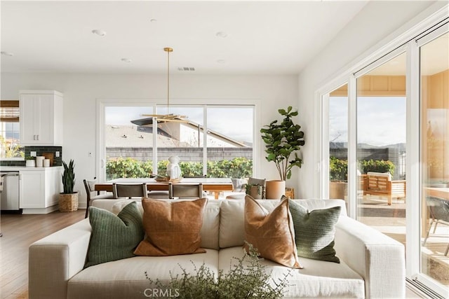 living area featuring plenty of natural light, visible vents, and wood finished floors