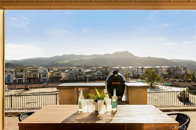 balcony with a residential view, outdoor dining area, area for grilling, and a mountain view