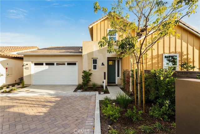 view of front of property featuring stucco siding, decorative driveway, and a garage