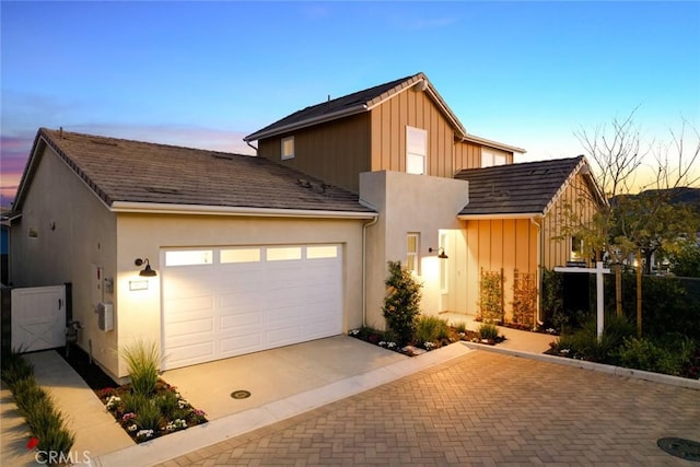 view of front of property with board and batten siding, stucco siding, driveway, and a garage