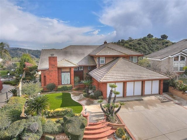 view of front of property with an attached garage, fence, driveway, and a chimney