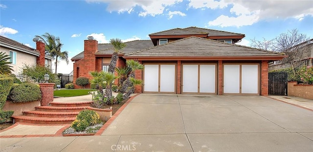 view of front of house with a tiled roof, concrete driveway, and fence