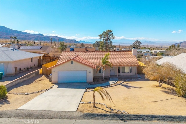 view of front of home with concrete driveway, a tiled roof, an attached garage, a mountain view, and stucco siding