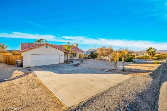 view of front of home with a garage, driveway, a chimney, fence, and stucco siding