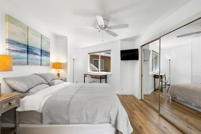 bedroom with ceiling fan, wood finished floors, baseboards, ornamental molding, and a closet