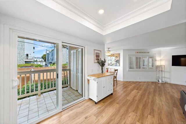 entryway featuring baseboards, ceiling fan, a tray ceiling, crown molding, and light wood-style floors