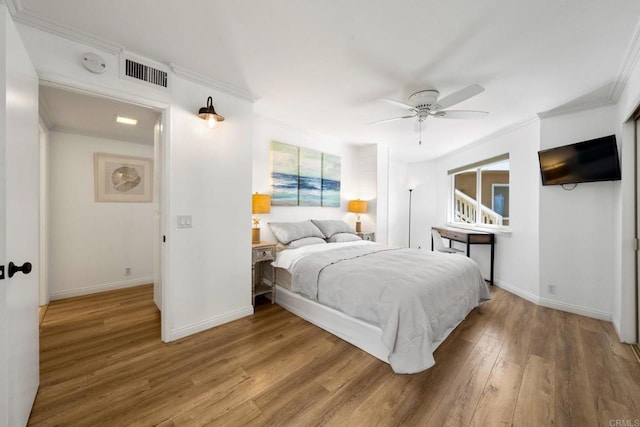 bedroom featuring crown molding, visible vents, ceiling fan, wood finished floors, and baseboards