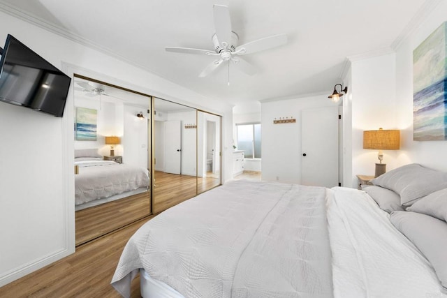 bedroom with a ceiling fan, ensuite bath, ornamental molding, wood finished floors, and a closet