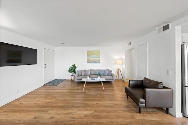 living area with light wood-style floors, visible vents, and ornamental molding