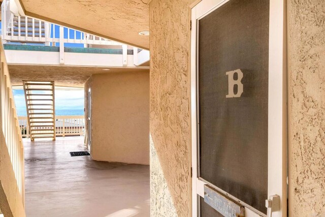 view of exterior entry featuring a balcony and stucco siding