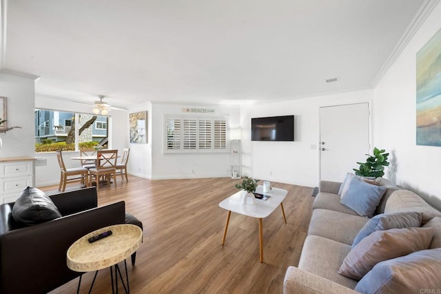 living room featuring light wood-type flooring, a ceiling fan, and ornamental molding