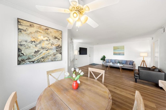 dining space with ornamental molding, baseboards, a ceiling fan, and wood finished floors
