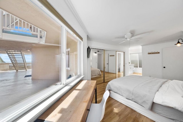 bedroom featuring a ceiling fan, wood finished floors, access to outside, a closet, and crown molding