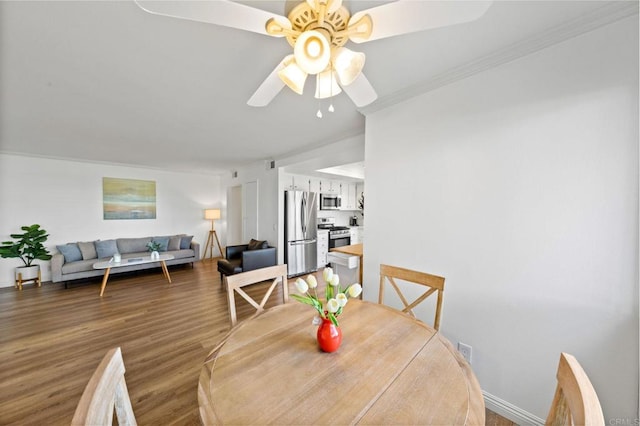 dining area featuring wood finished floors, ornamental molding, and ceiling fan