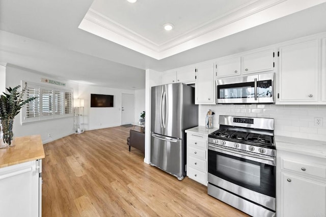 kitchen featuring decorative backsplash, open floor plan, light wood-type flooring, stainless steel appliances, and light countertops