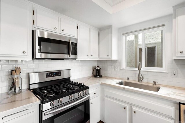1118 S Pacific St Unit B, Oceanside, CA 92054 - kitchen with appliances with stainless steel finishes, a sink, white cabinets, and tasteful backsplash