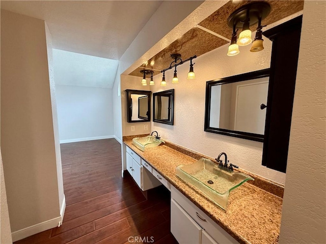 bathroom featuring lofted ceiling, a textured wall, wood finished floors, and baseboards