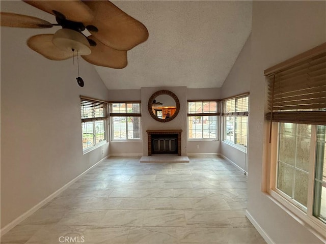 unfurnished living room with baseboards, ceiling fan, vaulted ceiling, a textured ceiling, and a brick fireplace