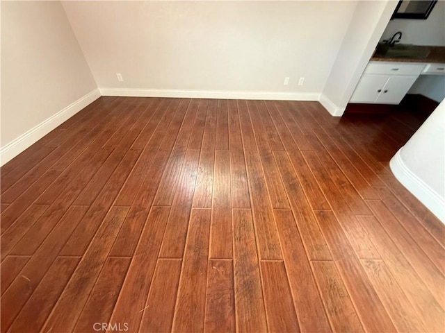 interior space featuring a sink, baseboards, and wood finished floors