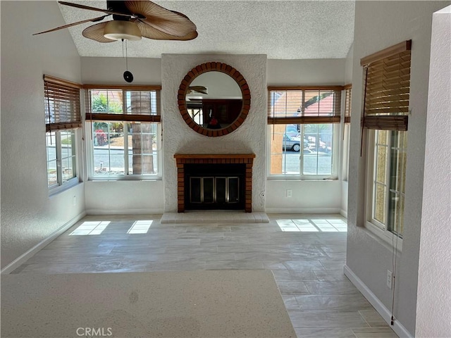 unfurnished living room featuring lofted ceiling, a fireplace, a textured ceiling, and baseboards