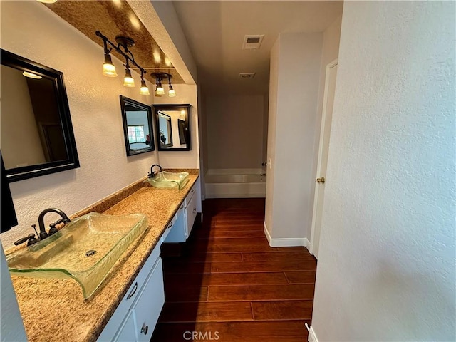 bathroom featuring double vanity, a sink, visible vents, and wood tiled floor