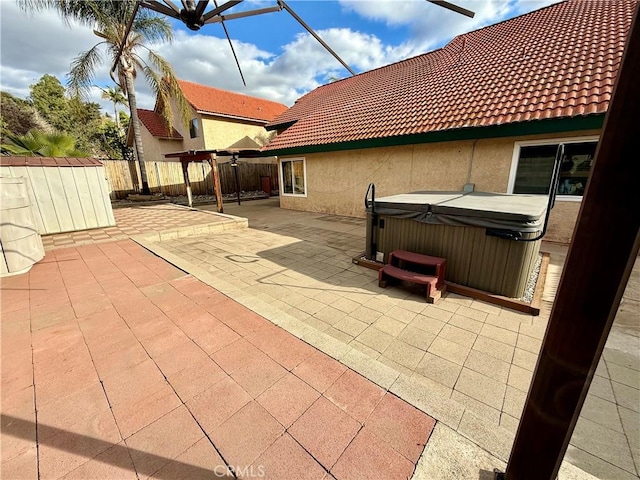 view of patio / terrace with an outbuilding, fence, a hot tub, and a storage unit