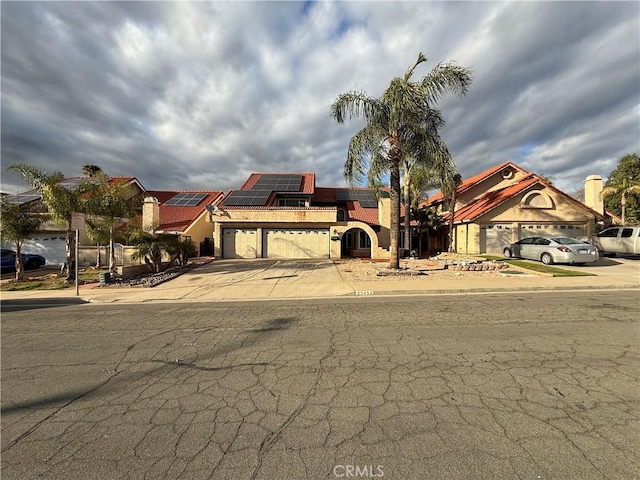 view of front facade featuring a garage, concrete driveway, and roof mounted solar panels