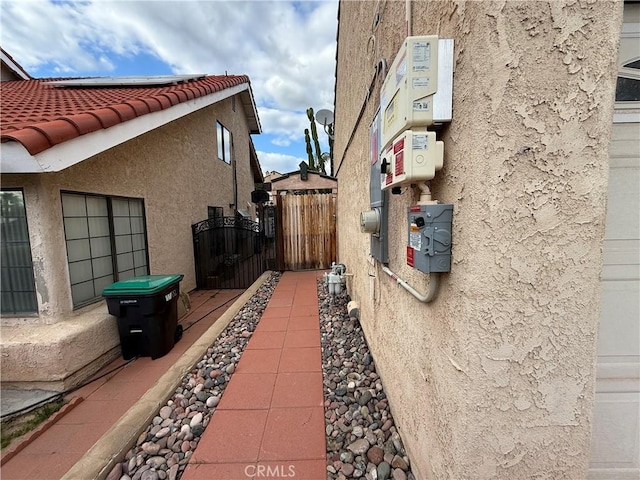 view of side of home featuring a tile roof, a gate, and stucco siding