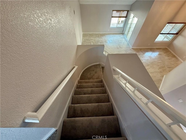 staircase with baseboards and a textured wall