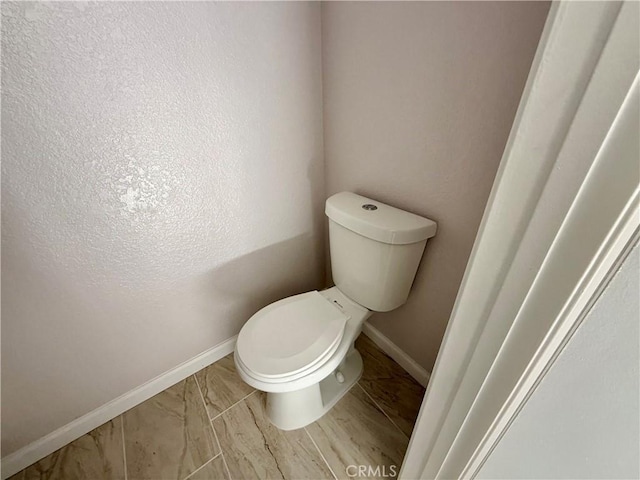 bathroom with toilet and baseboards