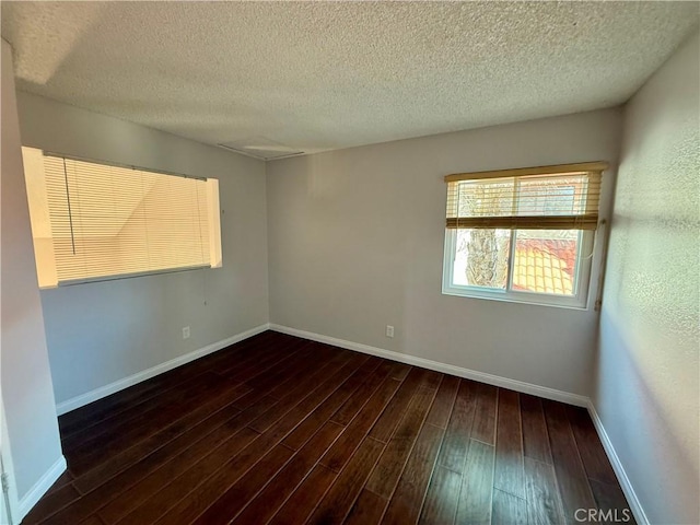 unfurnished room featuring a textured ceiling, baseboards, and wood finished floors