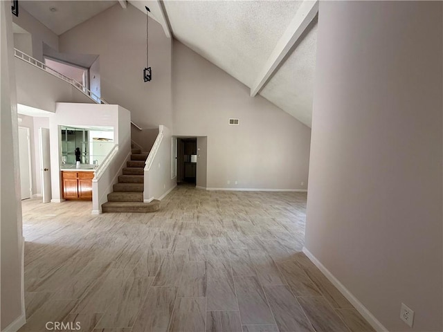 unfurnished living room featuring baseboards, beam ceiling, stairway, and wood finished floors