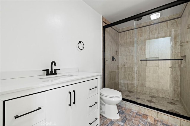 full bathroom featuring stone finish floor, a shower stall, toilet, and vanity