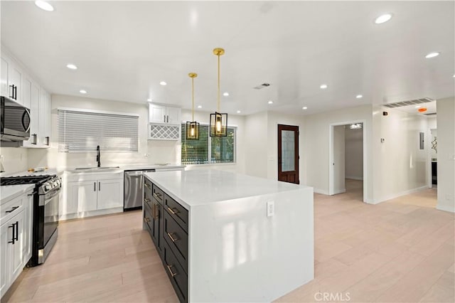 kitchen featuring appliances with stainless steel finishes, white cabinets, and a sink