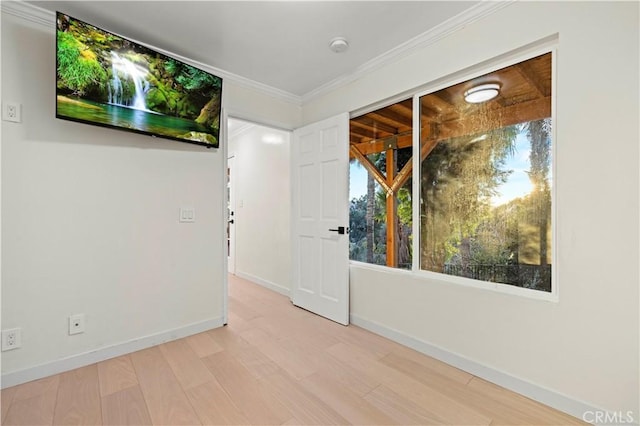 empty room featuring baseboards, crown molding, and wood finished floors