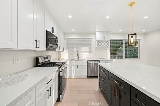 kitchen featuring appliances with stainless steel finishes, light countertops, white cabinets, and a sink