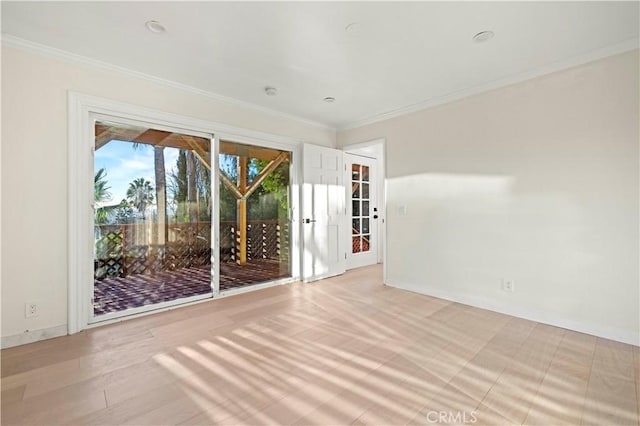 spare room featuring baseboards, crown molding, and wood finished floors