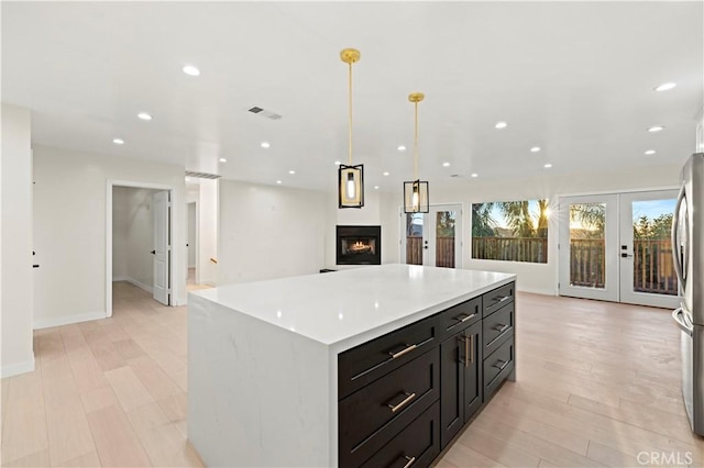 kitchen featuring french doors, light countertops, visible vents, light wood-style floors, and open floor plan