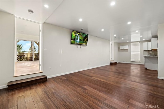 unfurnished living room featuring recessed lighting, dark wood-style flooring, and baseboards