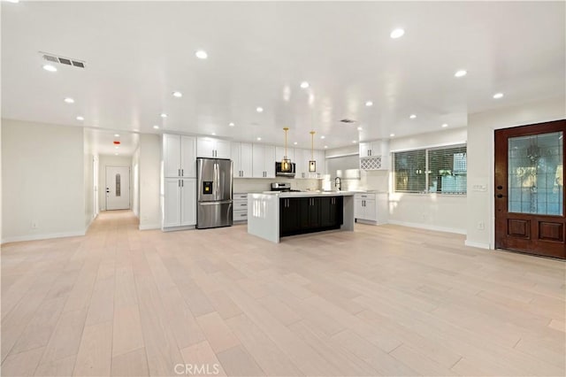 kitchen with visible vents, white cabinets, a center island, stainless steel appliances, and light countertops