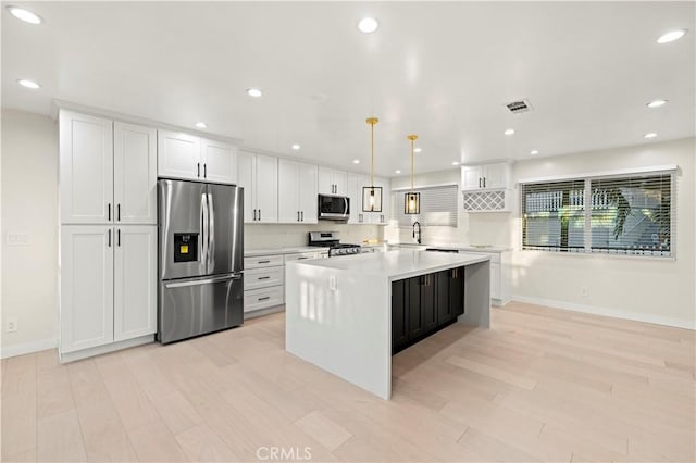 kitchen featuring visible vents, appliances with stainless steel finishes, a center island, light countertops, and white cabinetry