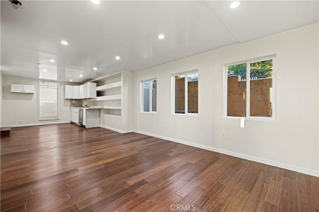 unfurnished living room with recessed lighting, a sink, dark wood finished floors, and baseboards