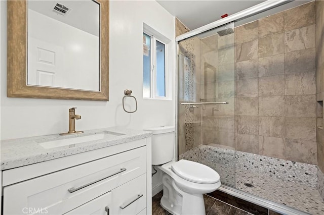 full bath with toilet, wood finished floors, vanity, visible vents, and a stall shower